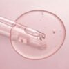 Pipette mit klarem Serum auf rosafarbenem Hintergrund
