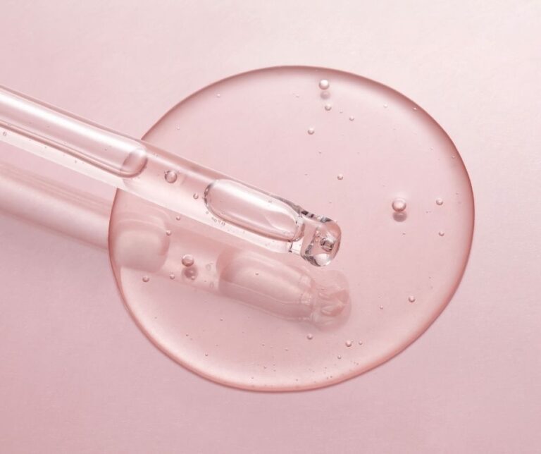Pipette mit klarem Serum auf rosafarbenem Hintergrund