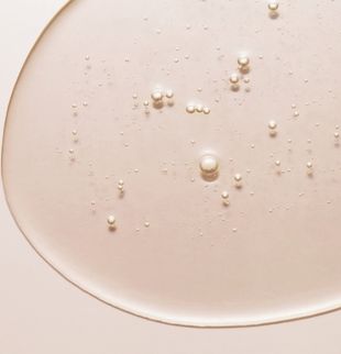 Nahaufnahme eines beigefarbenen Serums auf hellem Hintergrund