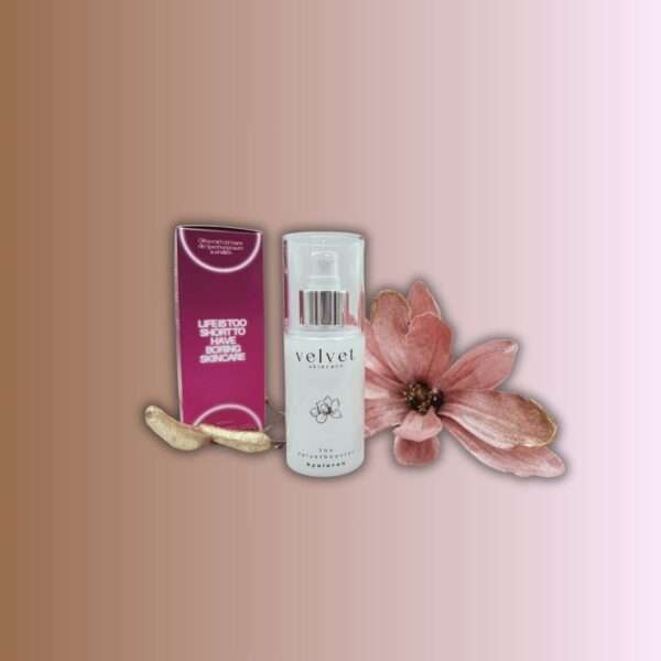 Velvetbooster zwischen rötlicher Verpackung und altrosafarbener Magnolienblüte mit vergoldetem Ast stehen vor hellbraunem Hintergrund