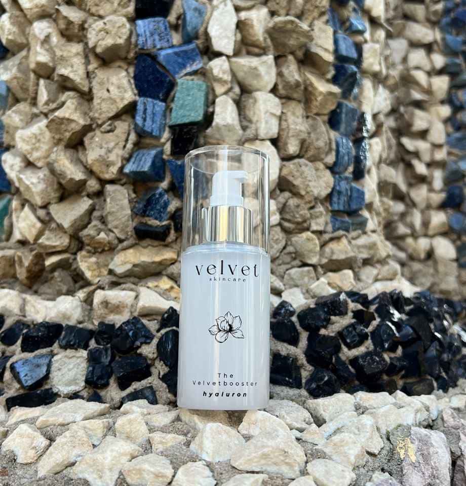 Velvet Skincare ‚The Velvet Booster Hyaluron‘ Flakon vor steiniger Mosaikstruktur in Beige-, Blau- und Schwarztönen, aufgenommen in der Eremitage Bayreuth.
